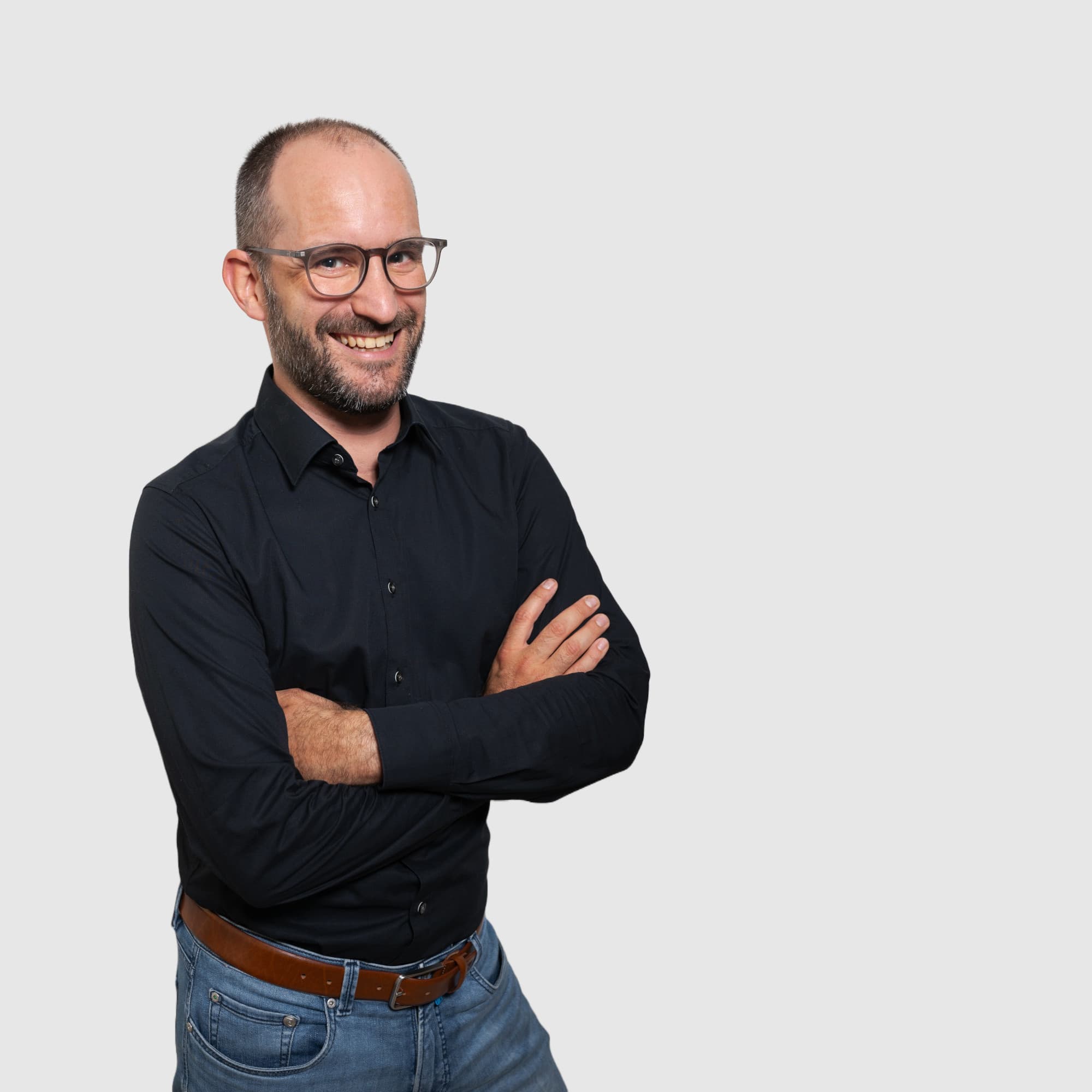 Männliche Person, mit verschränkten Armen, freundlich in die Kamera blickend